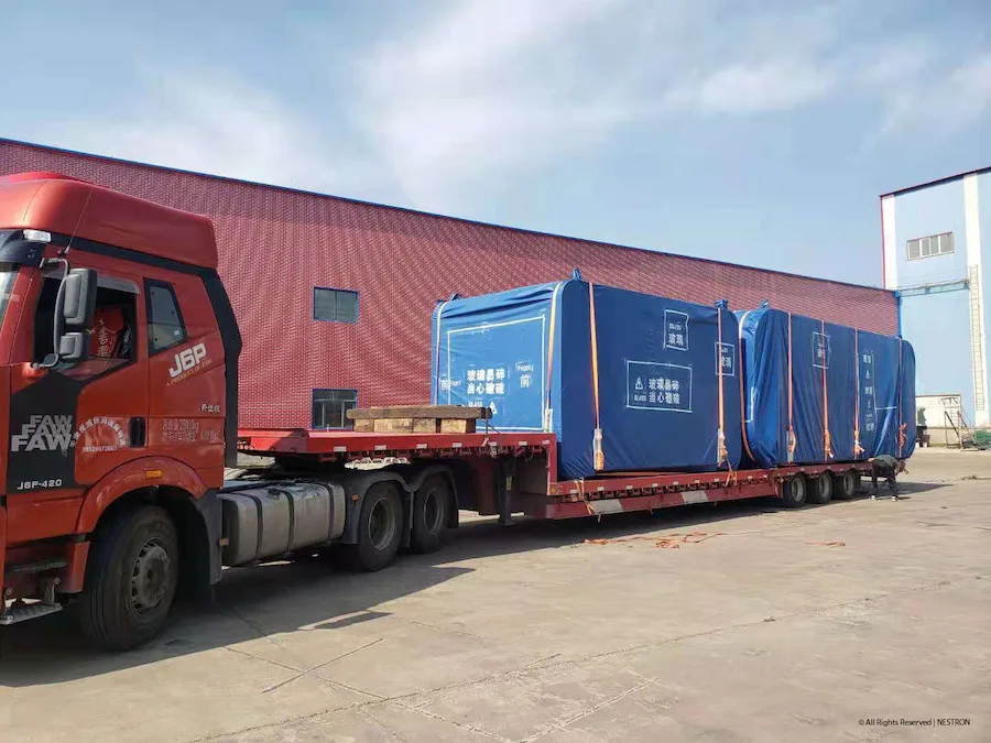Modular home shipping containers and transport truck outside an industrial building
