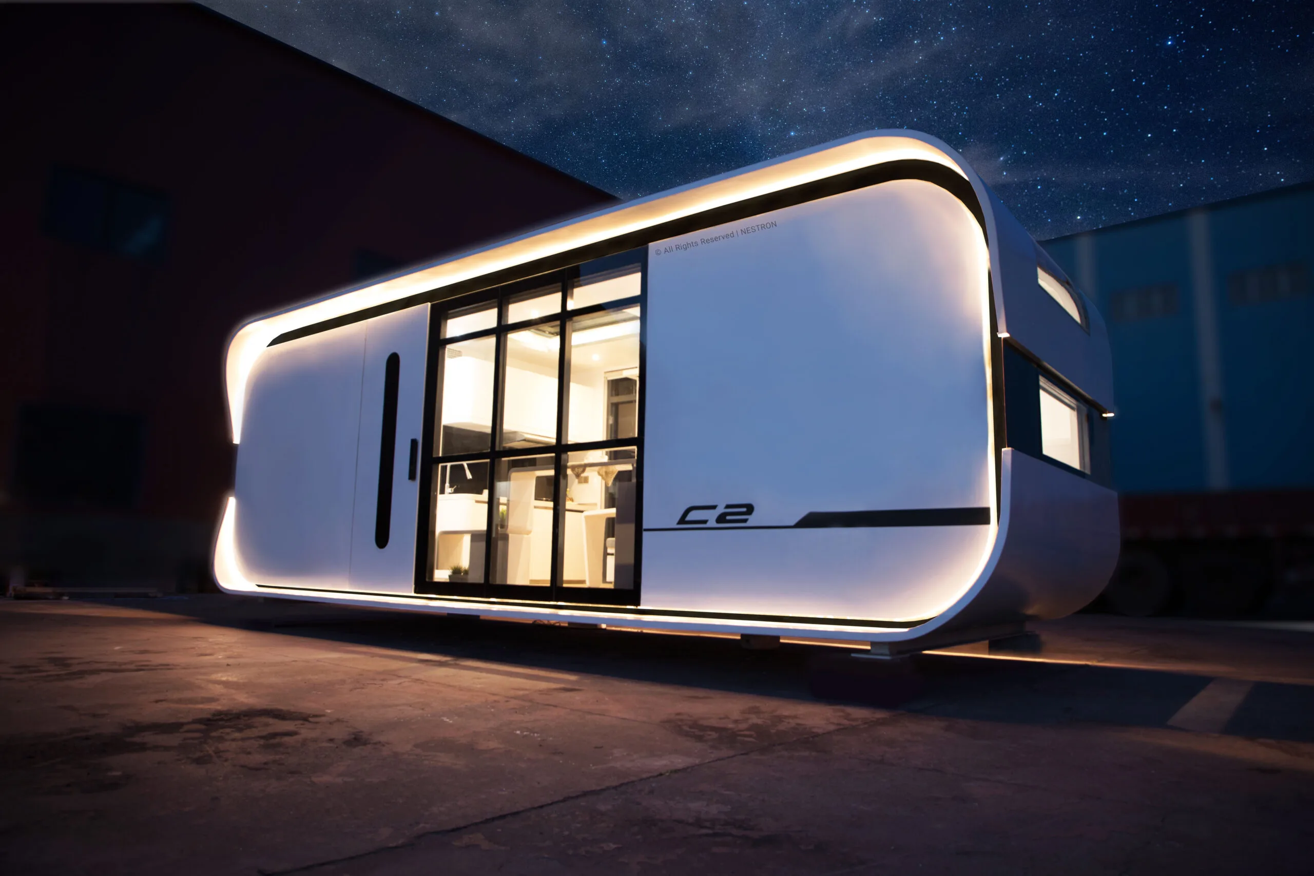 Exterior night rendering of a Nestron modular home with illuminated windows and a rounded white facade