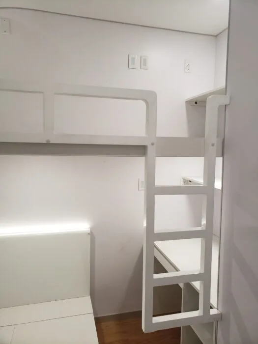 Nestron smart home interior with a white bunk bed, integrated ladder, built-in storage, and compact sleeping area