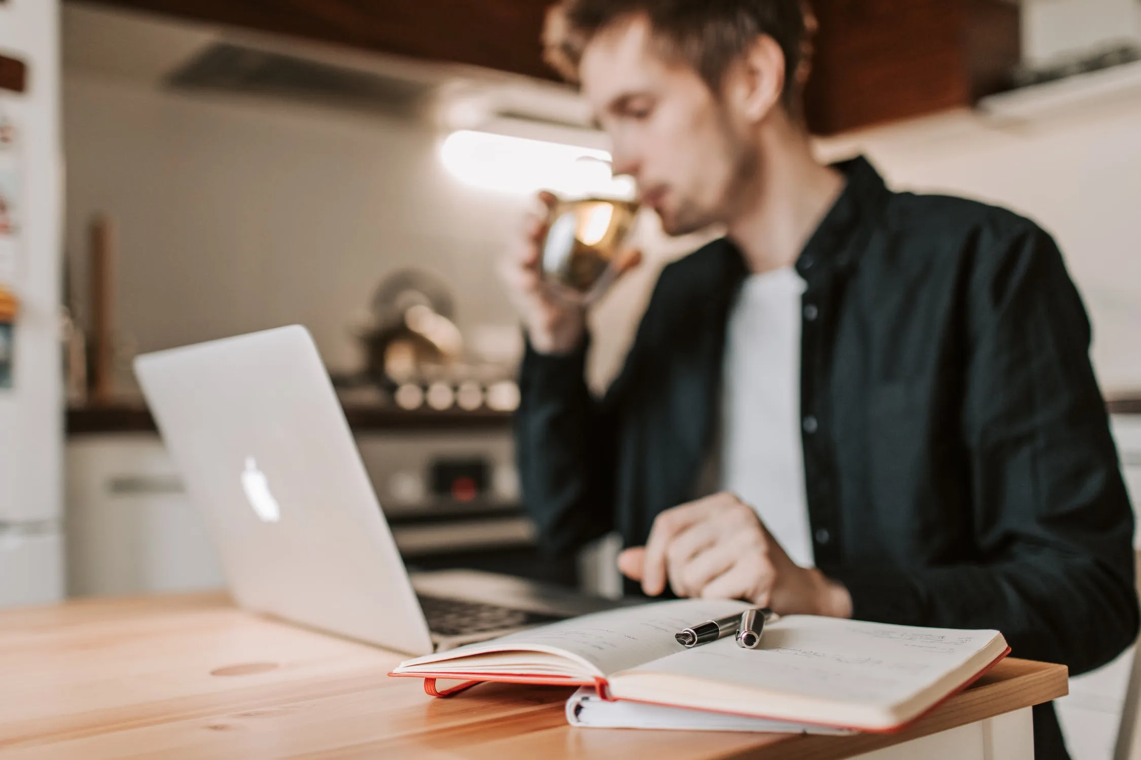 Person working on a laptop while drinking coffee in a home workspace