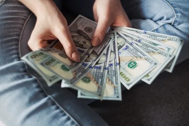 Close-up of hands counting U.S. dollar bills over financial documents
