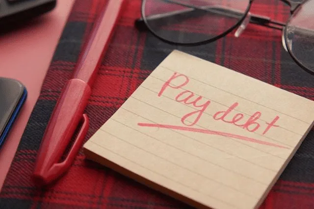 Close-up of a payday note beside a calculator and financial documents