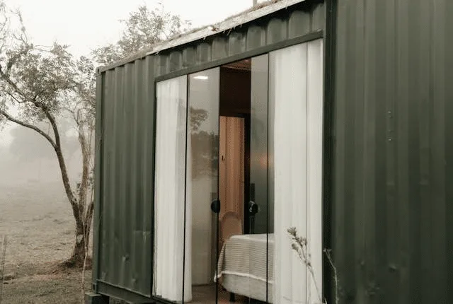Exterior view of a modern modular home with dark siding, wood accents, and large windows