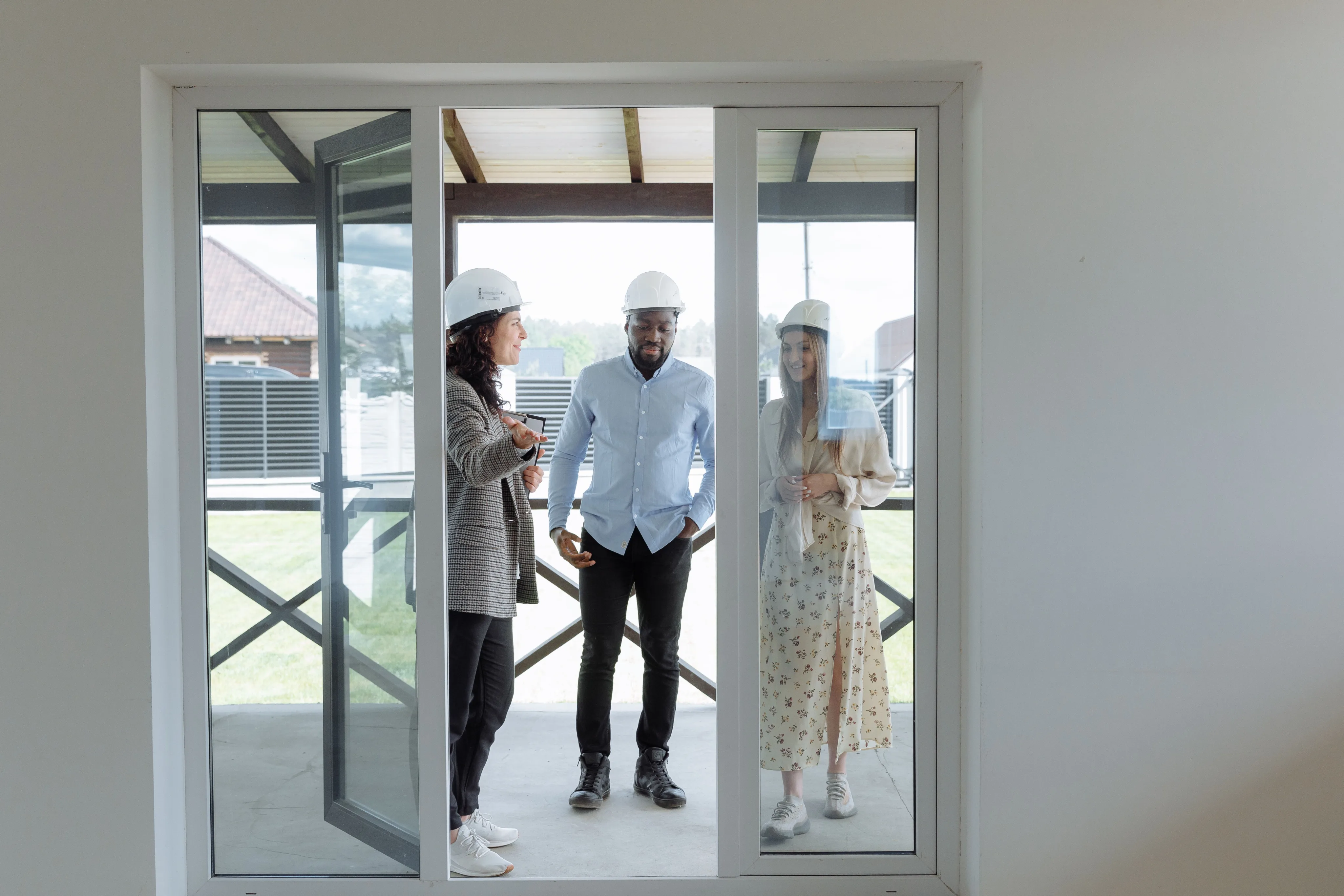 Two people standing in the doorway of a modern home with large glass doors
