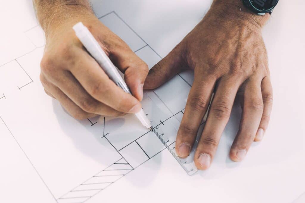 Person drawing lines on paper with a ruler and a pen