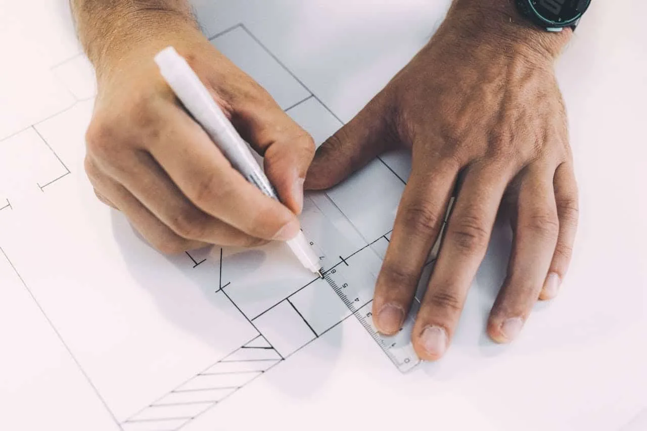 Close-up of hands sketching architectural plans for a backyard studio