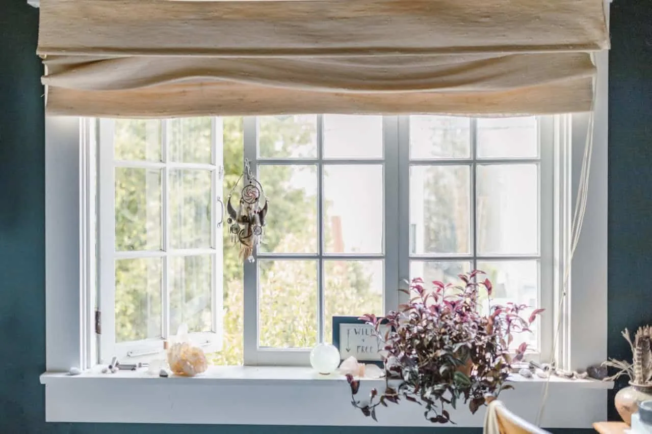 Cozy backyard studio interior with a large window, natural light, and flowers on a table