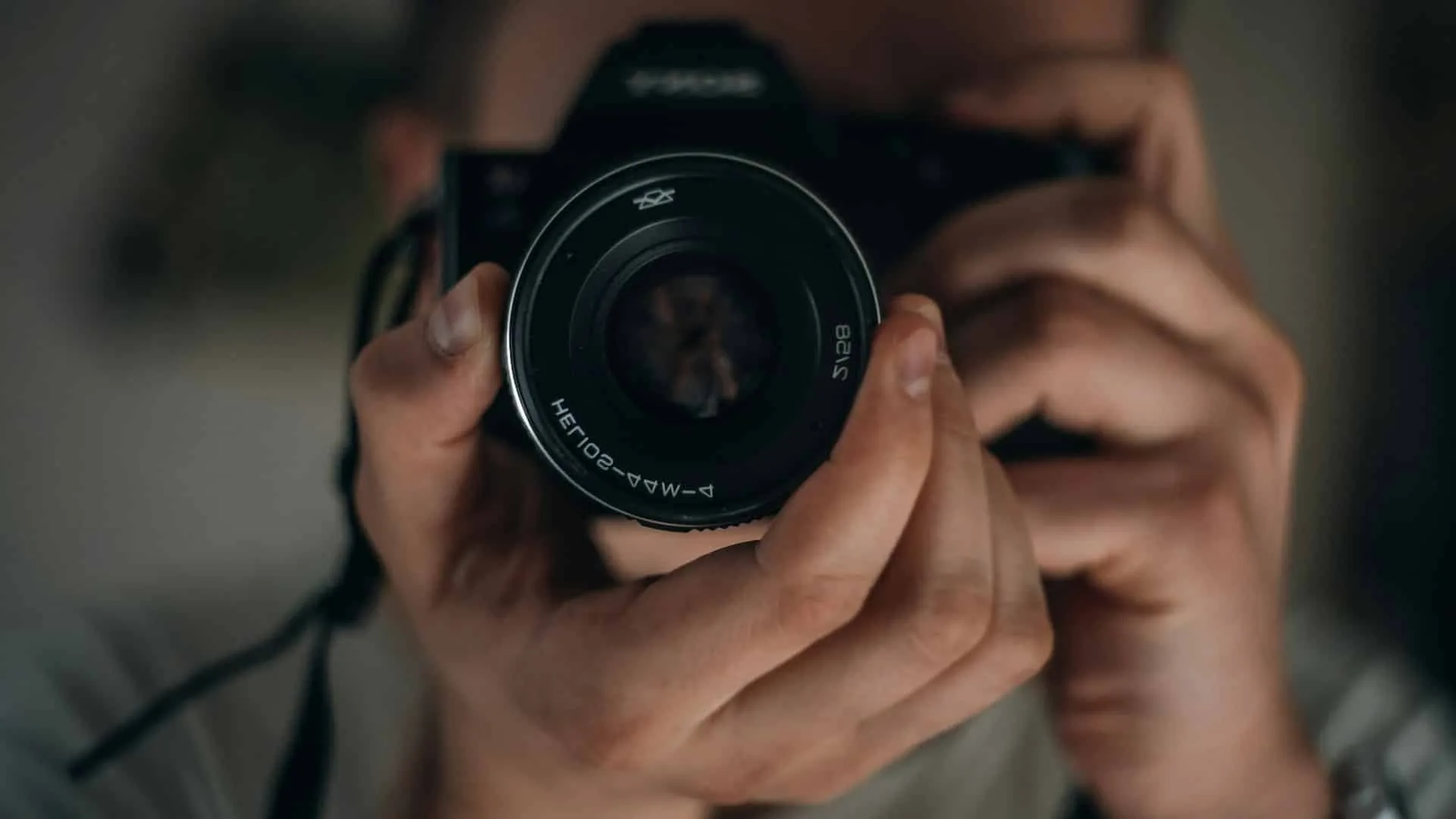 Close-up of a person holding a digital camera with the lens facing forward