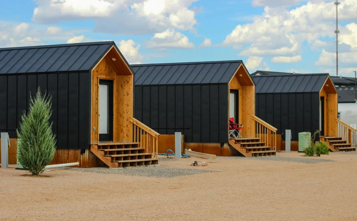 Exterior view of a compact backyard ADU with wood siding and a dark roof under a blue sky
