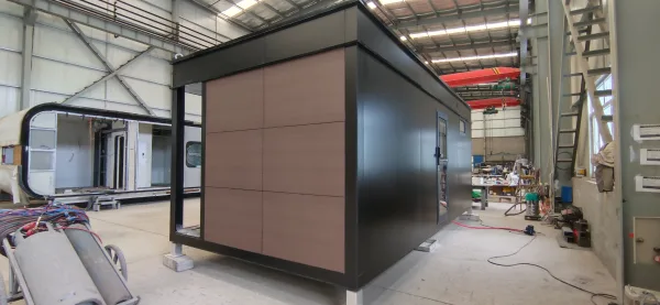 Nestron Legend One modular home exterior with a taupe accent panel and matte black siding, photographed on the factory floor