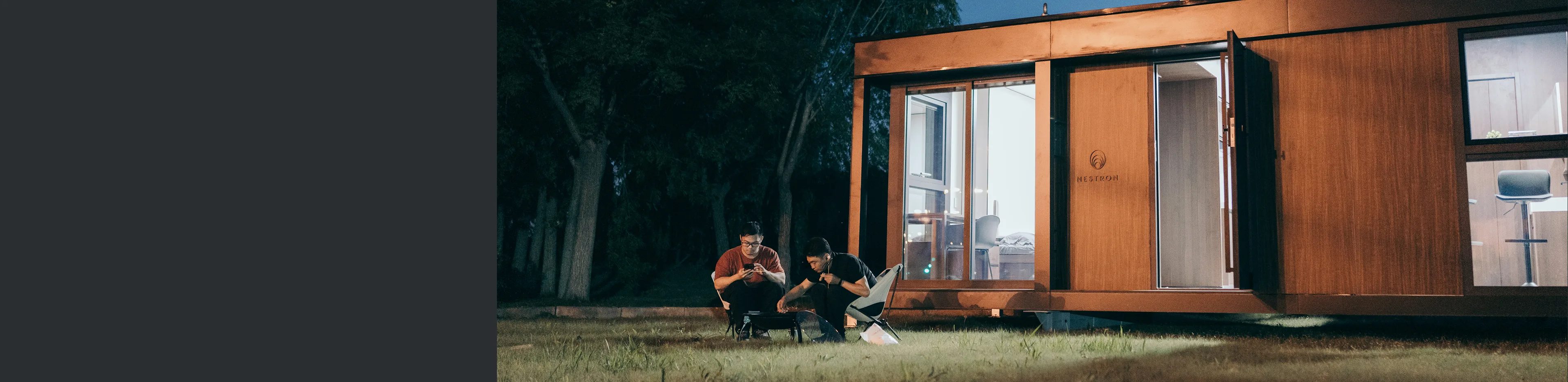 People relaxing outside a modern modular home in a wooded setting