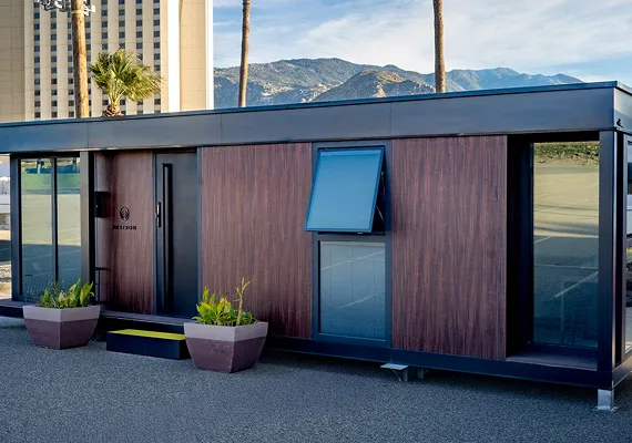 Exterior view of a compact modular home with dark siding and a blue accent panel