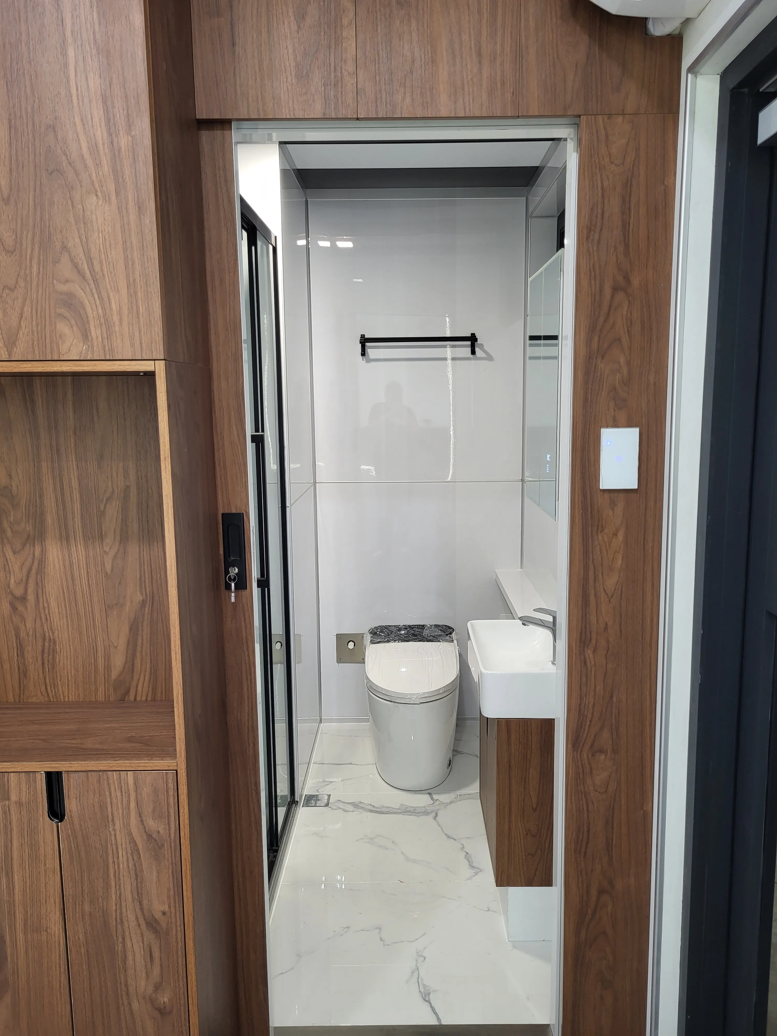 Nestron Cube One bathroom rendering with a white toilet, wood wall panels, and compact storage