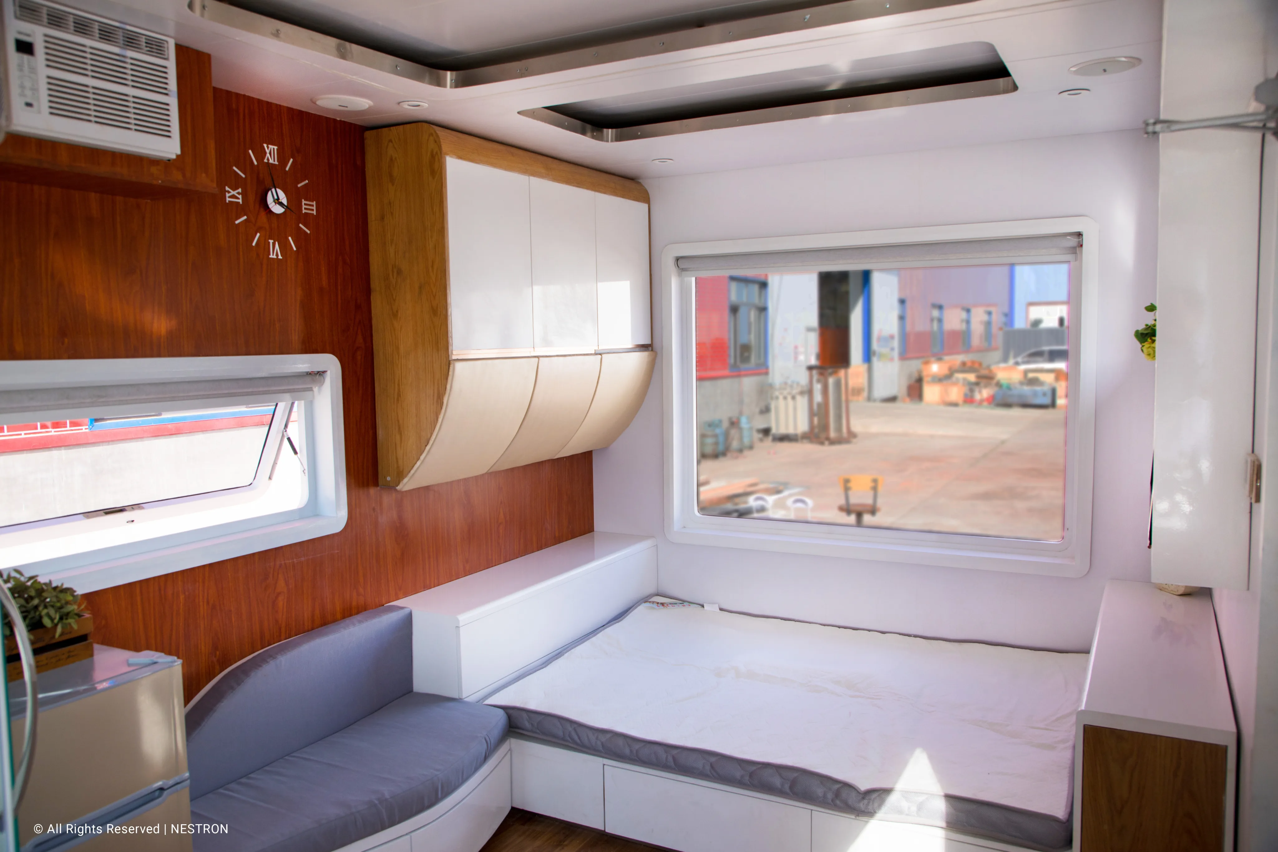 Nestron Cube One living and sleeping area rendering with gray seating, white cabinetry, and orange wall accents