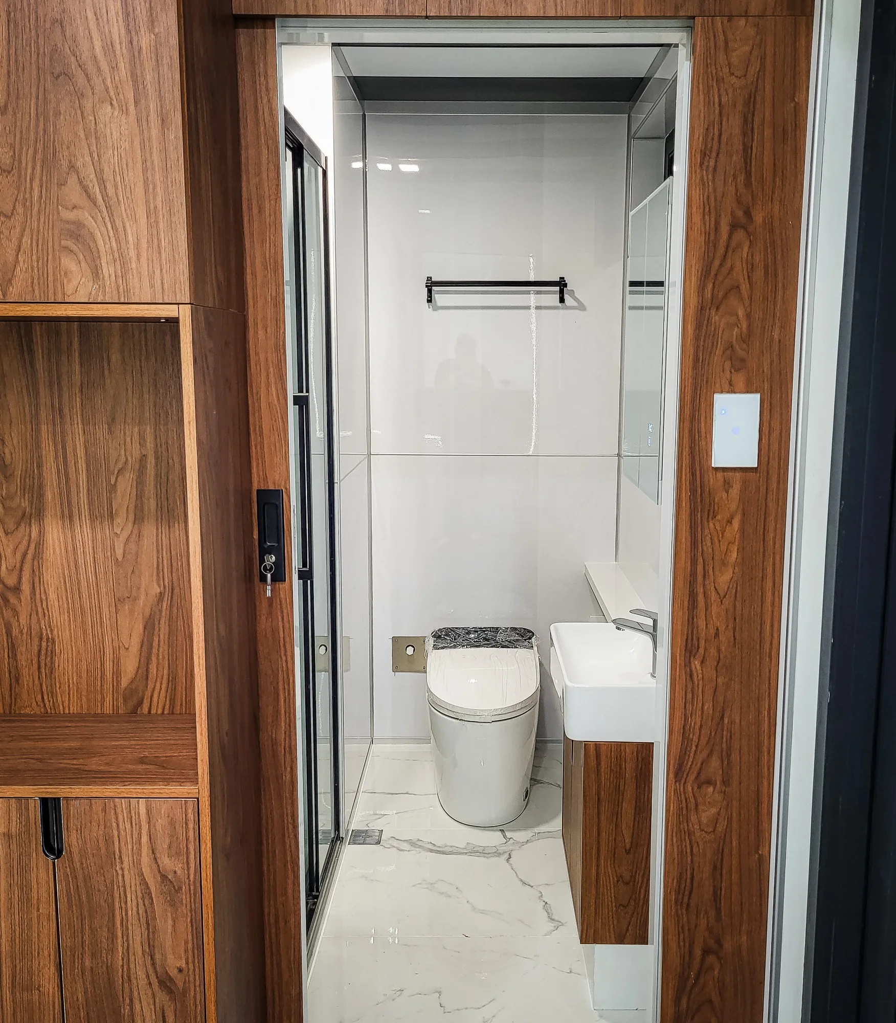 Nestron modular home bathroom with walnut paneling, toilet, and vanity sink