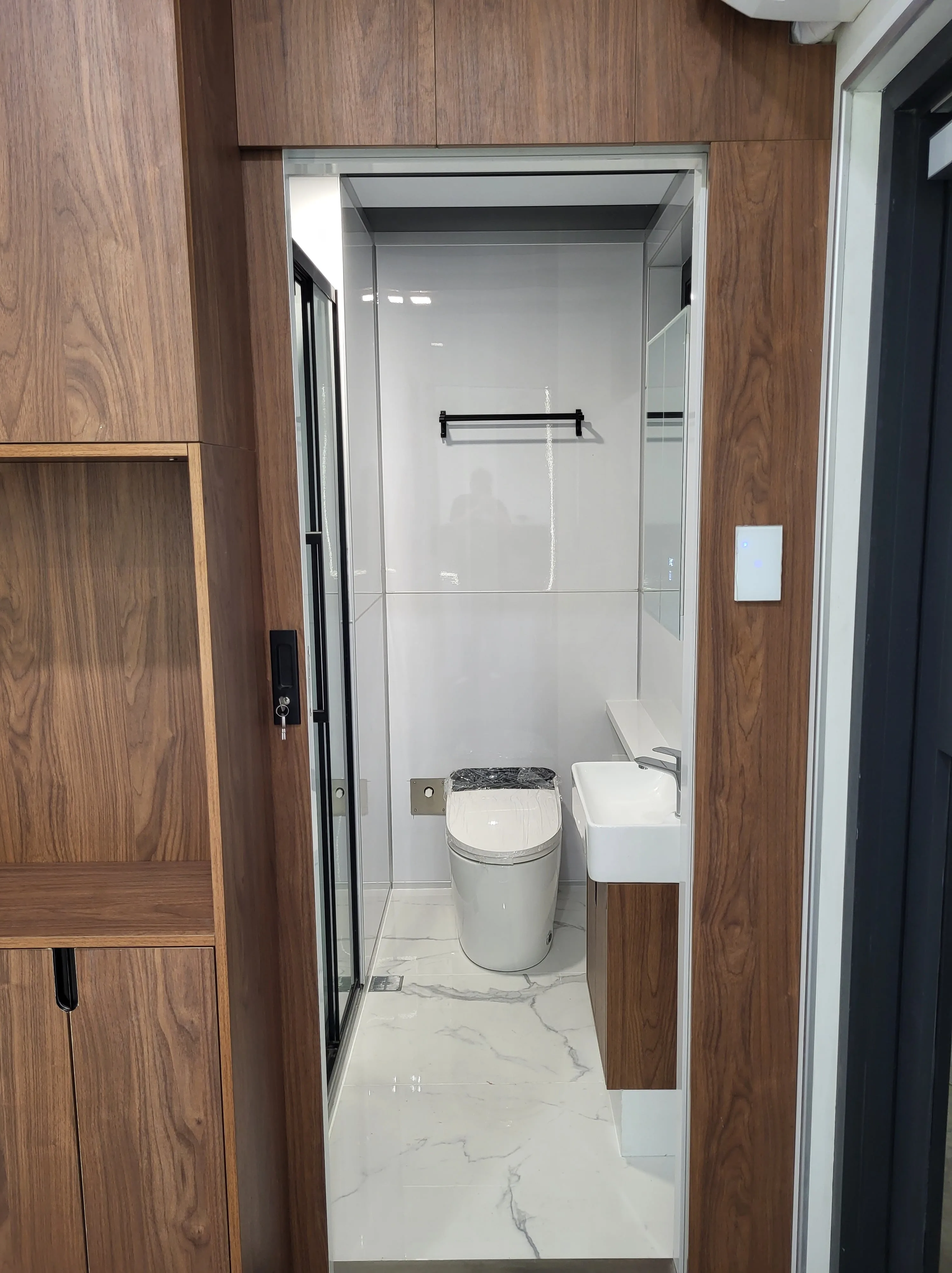 Nestron Cube One bathroom rendering with a white toilet, wood wall panels, and built-in storage