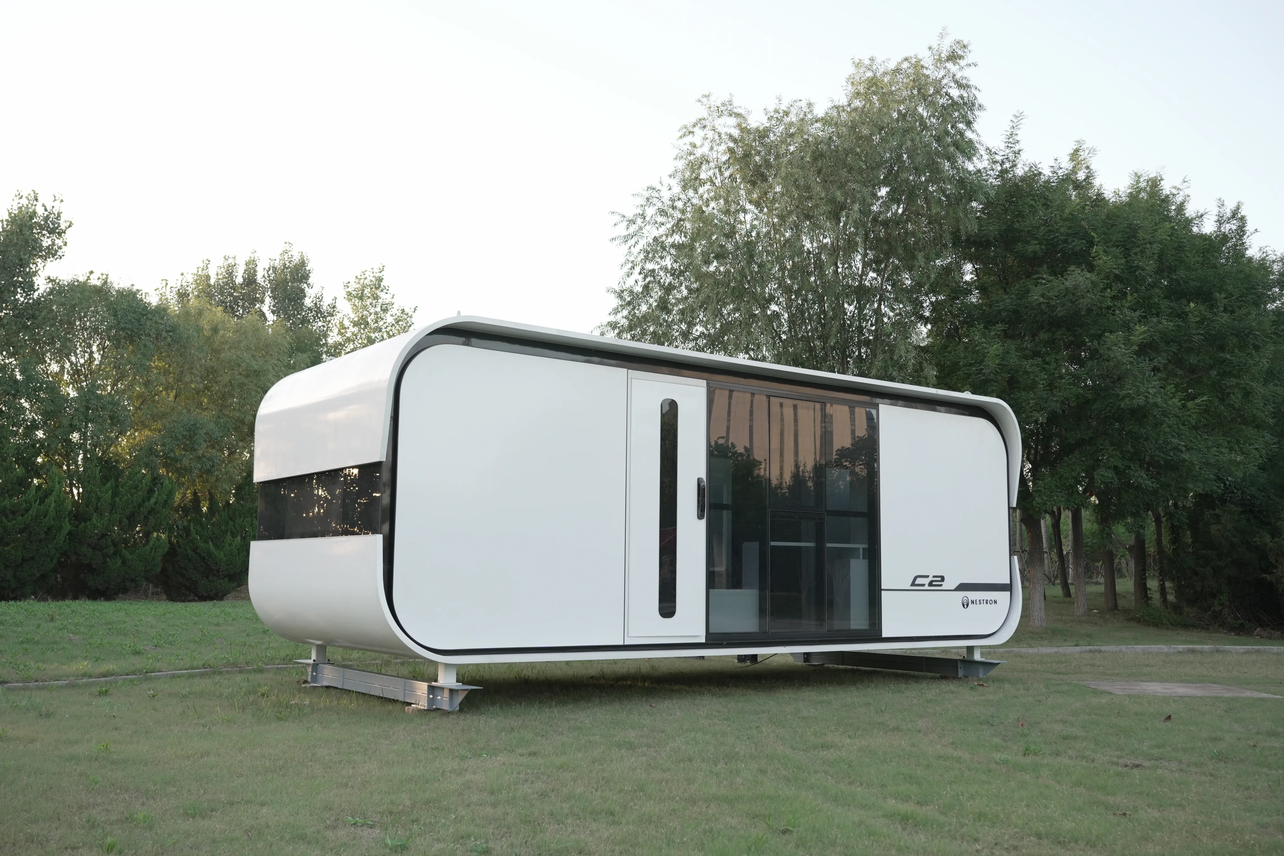 Nestron C2 modular home exterior on grass with surrounding trees