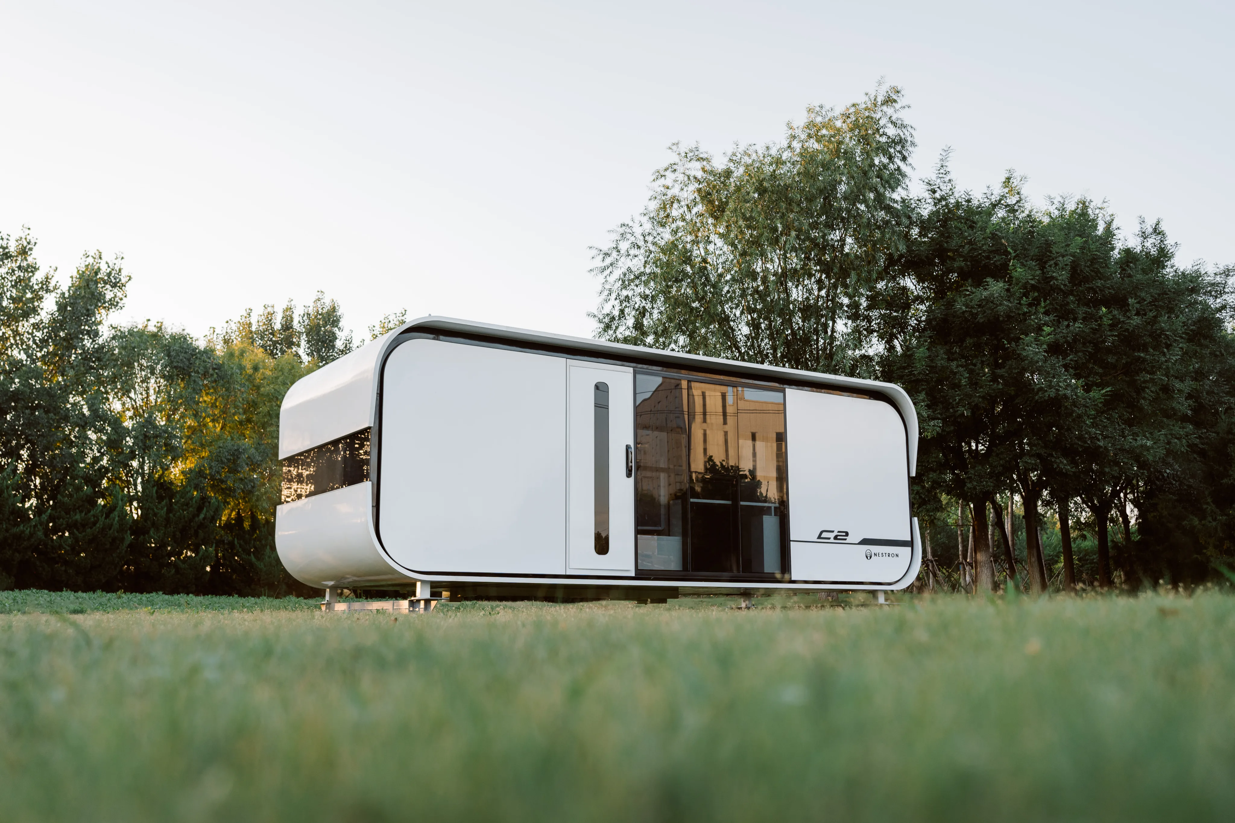 Nestron C2 modular home exterior on grass surrounded by trees