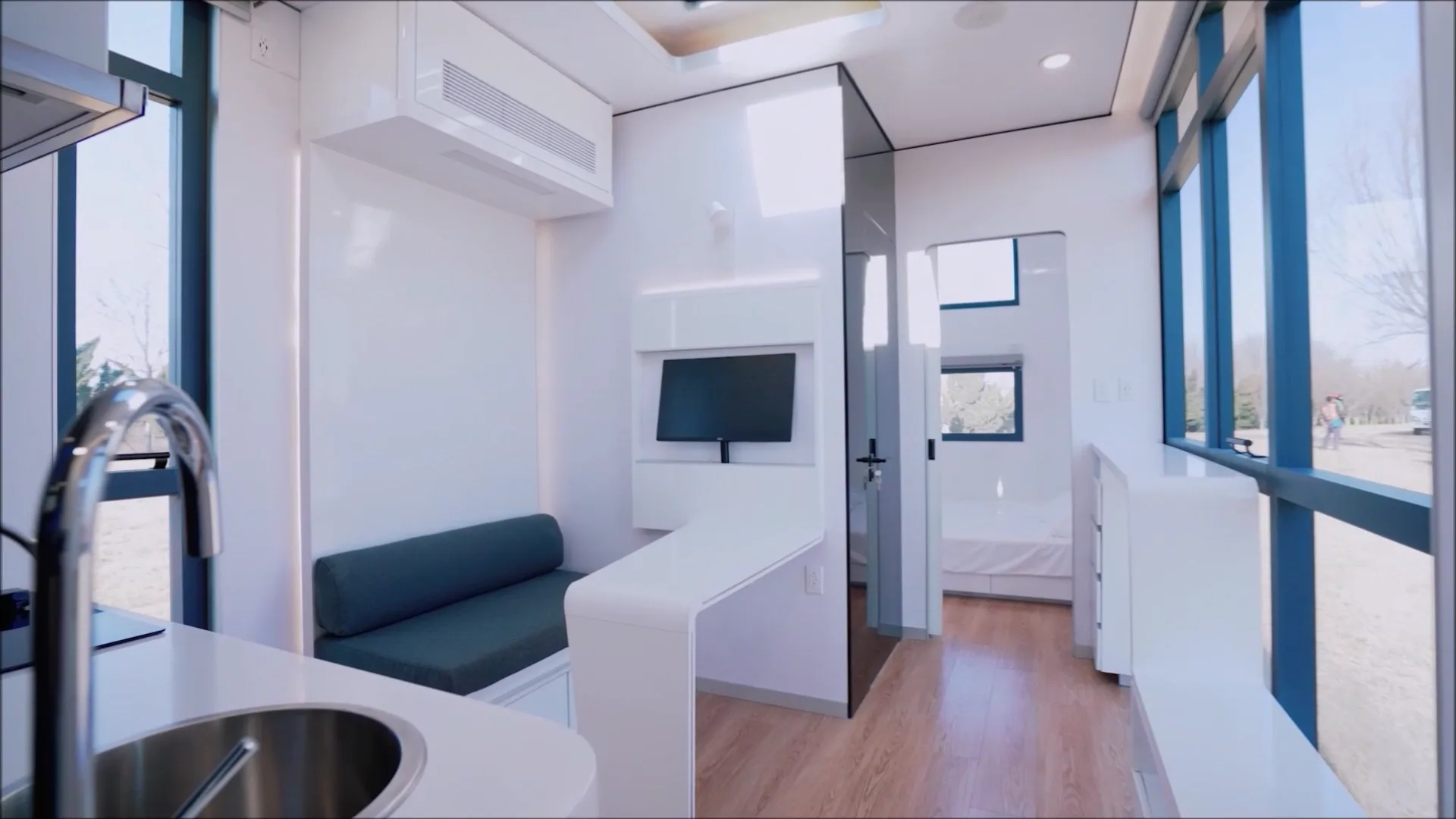 Nestron modular home interior with wall-mounted TV, lounge seating, and skylight, atmospheric feature
