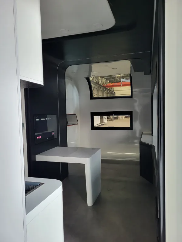 Nestron Cube Two X dinette area with a white fold-out table, black overhead cabinets, and dual windows