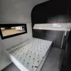 Nestron Cube Two X bedroom rendering with a bed, integrated shelving, dark wall panels, and a horizontal window