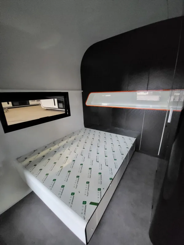 Nestron Cube Two X bedroom rendering with a bed, integrated shelving, dark wall panels, and a horizontal window