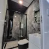 Nestron Cube Two X bathroom rendering with a glass shower enclosure, white vanity, toilet, and stone-look wall panels