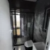 Nestron Cube Two X bathroom rendering with a glass shower enclosure, toilet, and dark stone-look wall panels