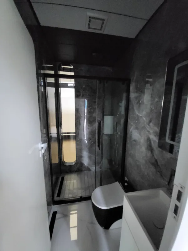 Nestron Cube Two X bathroom rendering with a glass shower enclosure, toilet, and dark stone-look wall panels