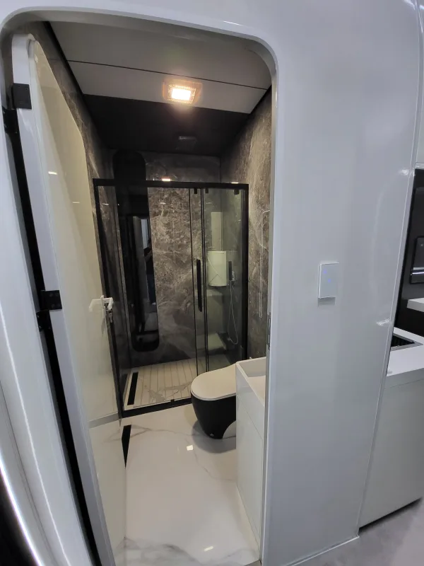 Nestron Cube Two X bathroom rendering with a glass shower enclosure, toilet, and dark interior finishes