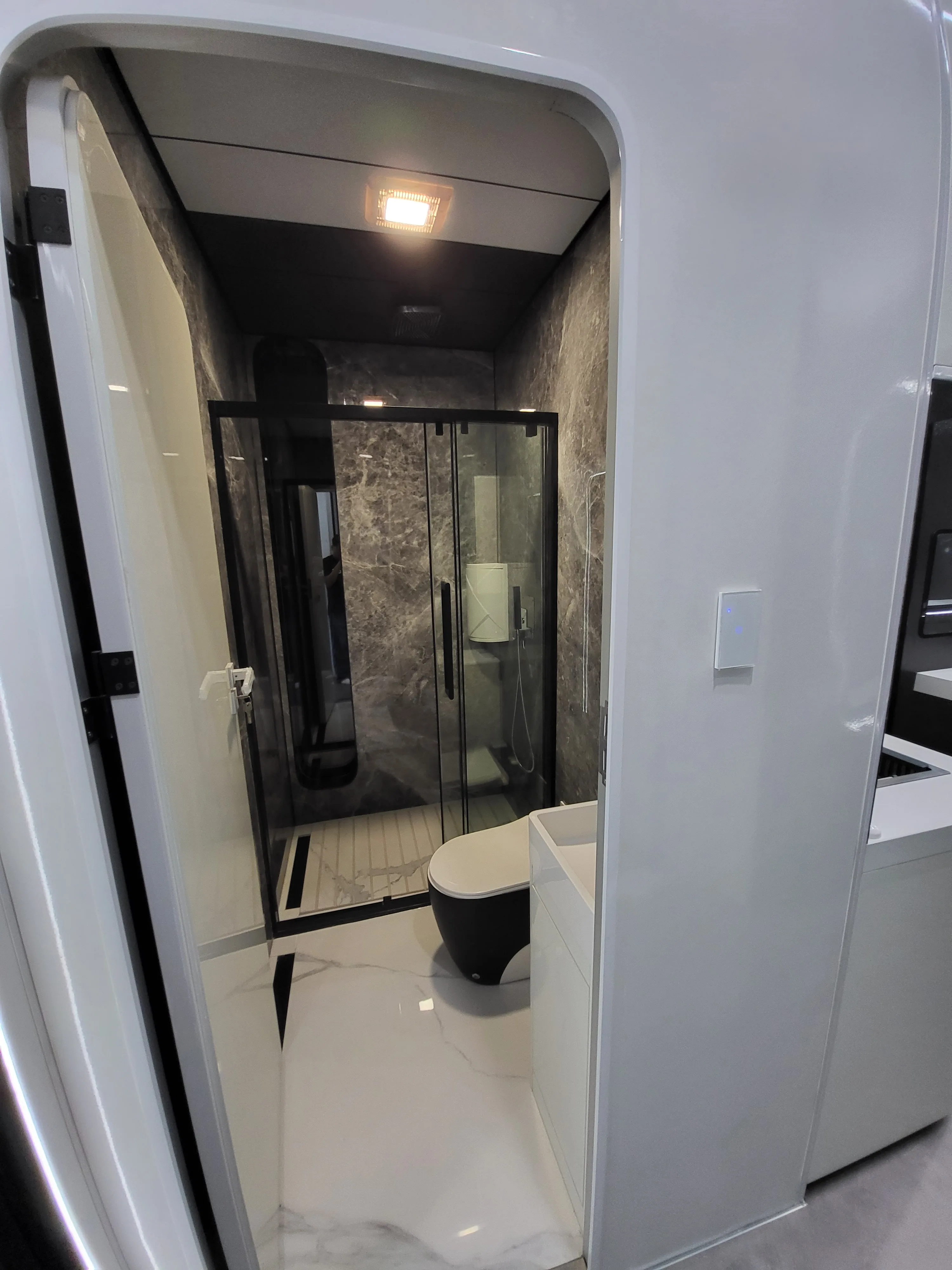 Nestron modular home bathroom with marble walls, glass shower, and toilet, atmospheric feature