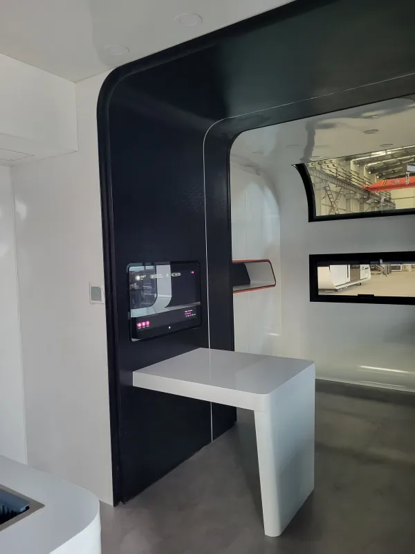 Nestron Cube Two X interior rendering with a compact table, dark cabinetry, and a large window