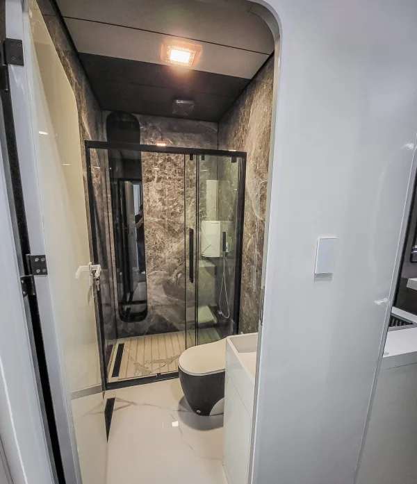 Nestron Cube Two X bathroom rendering with a glass shower enclosure, toilet, and dark interior finishes