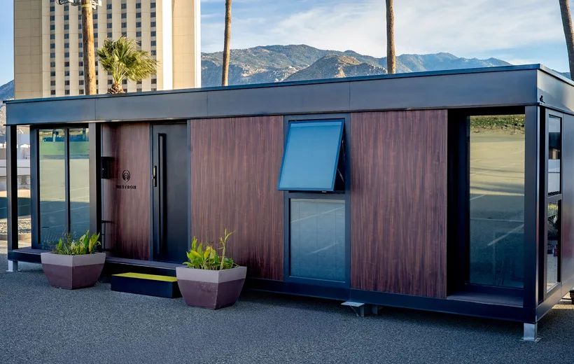 Exterior view of a modular building with dark siding, wood accents, and a blue upper panel