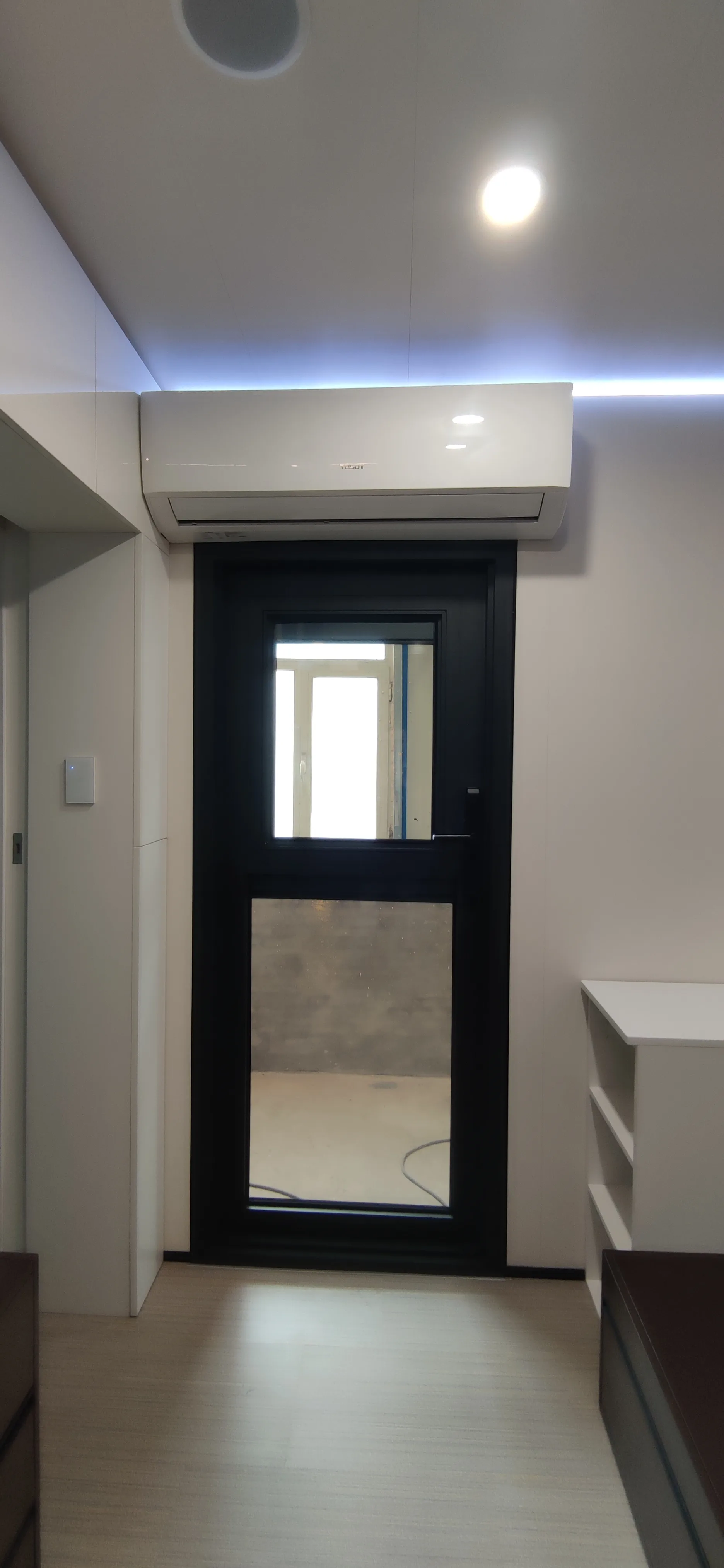 Nestron Legend One entry door with a glass panel and wall-mounted split air conditioning unit above