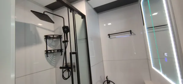 Nestron Legend One bathroom rendering with black shower fixtures, white tiled walls, and an entry door