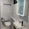 Nestron Legend One bathroom rendering with a white vanity, toilet, illuminated mirror, and black fixtures