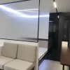 Nestron Legend One living area rendering with a beige sofa, illuminated wall panel, and dark interior accents