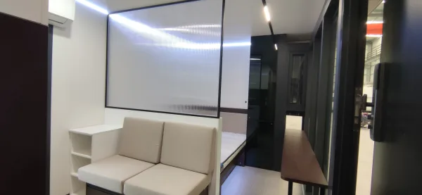 Nestron Legend One living area rendering with a beige sofa, illuminated wall panel, and dark interior accents