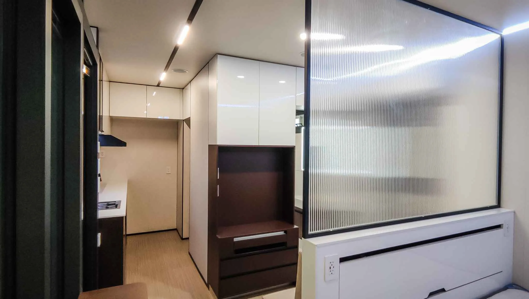 Nestron Legend One interior rendering showing a TV console, dark wood cabinetry, and mirrored partition