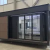 Front exterior rendering of the Nestron Legend One with large glass doors, dark trim, and wood facade panels