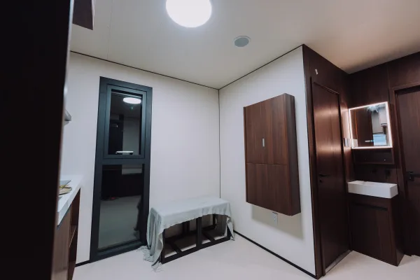 Nestron Legend Two interior rendering showing a compact room with white walls, dark wood panels, and recessed lighting