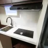 Close-up rendering of the Nestron Legend Two kitchen with a sink, black cooktop, white countertop, and range hood
