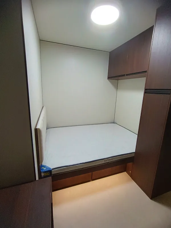 Nestron Legend Two bedroom rendering with a bed, white bedding, and dark wood wall panels