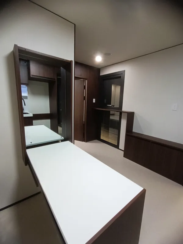 Nestron Legend Two interior rendering with a white dining table, dark wood cabinetry, and kitchen area