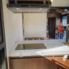 Nestron Legend Two kitchen interior with a cooktop, range hood, white countertop, and wood cabinetry
