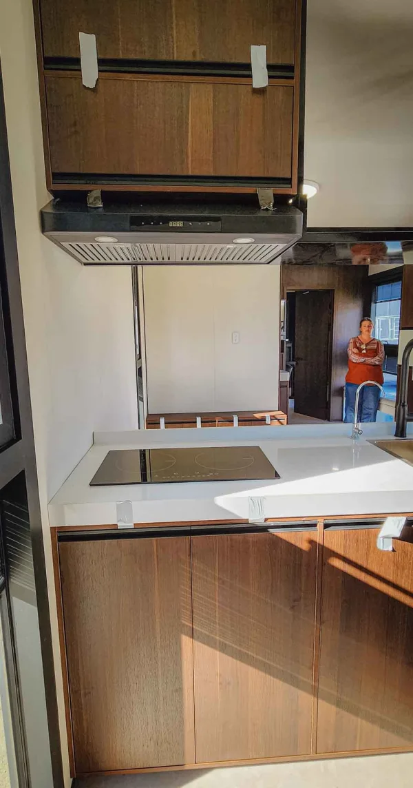 Nestron Legend Two kitchen interior with a cooktop, range hood, white countertop, and wood cabinetry