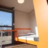 Nestron Legend Two bedroom rendering with a bed, large window, and orange interior accents