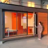 Nestron Legend Two exterior rendering with large glass doors, warm interior lighting, and people standing outside