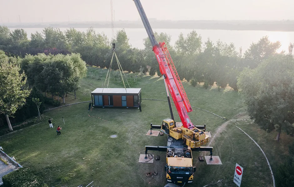 Crane installing a modular home unit at a wooded delivery site